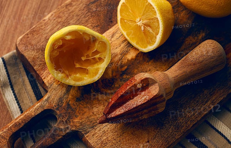Lemons and a wooden manual citrus juicer, on a chopping board, close-up, no people