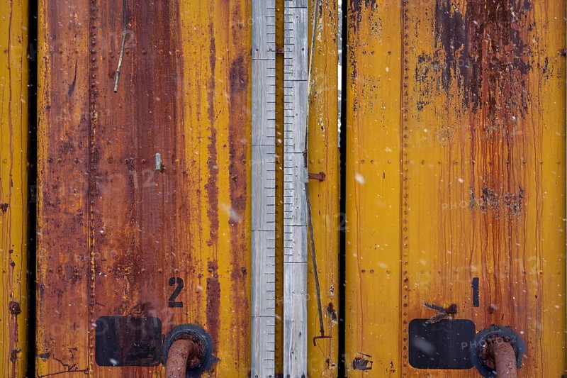 Rusted yellow tanks with numbering and level measurement bar, detailed view in case of snowfall, former Grytviken whaling station, South Georgia