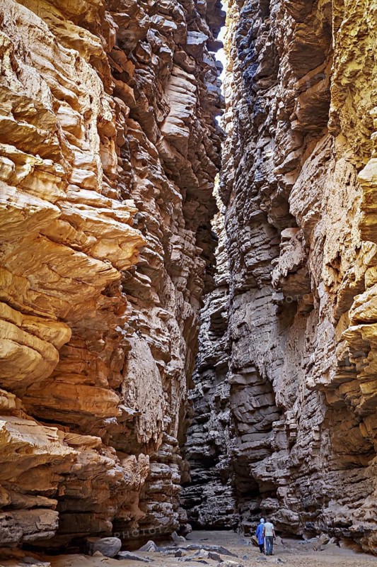 Deep, narrow gorge with dramatic incidence of light and a person surrounded by rocky walls, rocky gorge in the desert landscape of the Sahara in Algeria