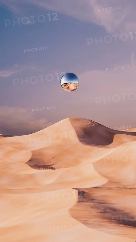 A unique desert landscape showcases soft dunes under a vast sky, with a metallic sphere suspended above the sand, creating a surreal atmosphere