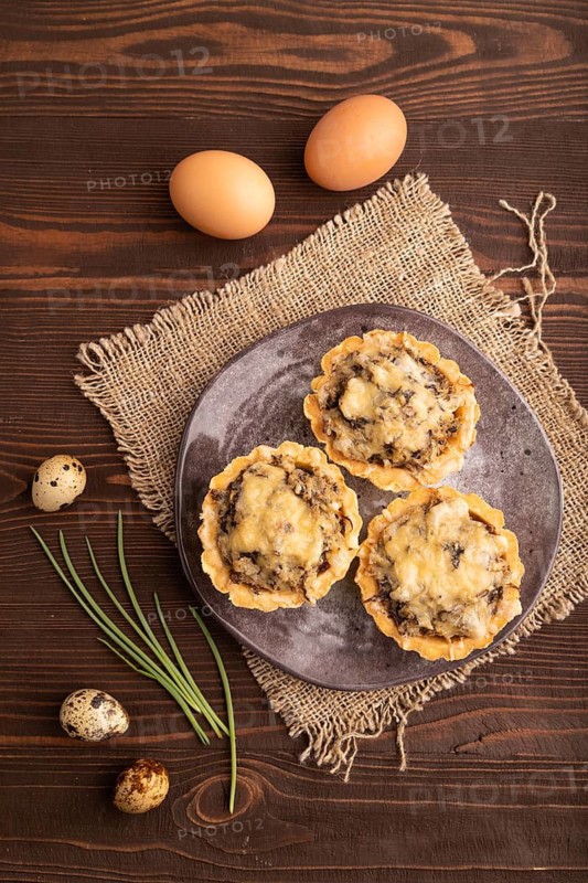 Tartlets with meat and cheese on brown wooden background and linen textile. top view, flat lay, close up