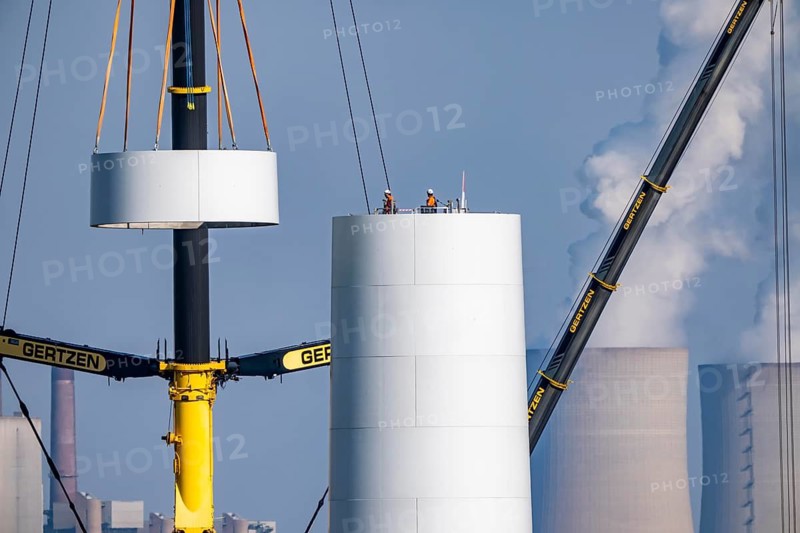 Construction site of the new Bedburg 3 wind farm, on recultivated open-cast mining site, 9 wind power plants with an output of 60 megawatts are newly built, installation of the wind turbine tower, in the background the Neurath lignite power plant, operated by RWE and the city of Bedburg, North Rhine-Westphalia, Germany