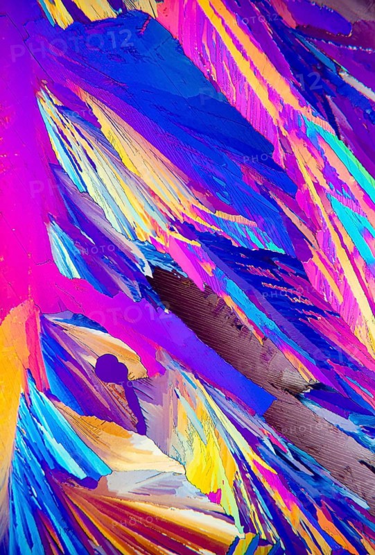 Microscopic image showcasing vivid Adipic acid, crystals in stunning shades of blue, purple, and red