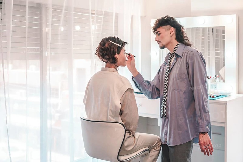 Professional makeup artist carefully applying eyeliner to a model's eye, enhancing her beauty in a bright and modern salon setting, showcasing diversity and inclusion in the beauty industry