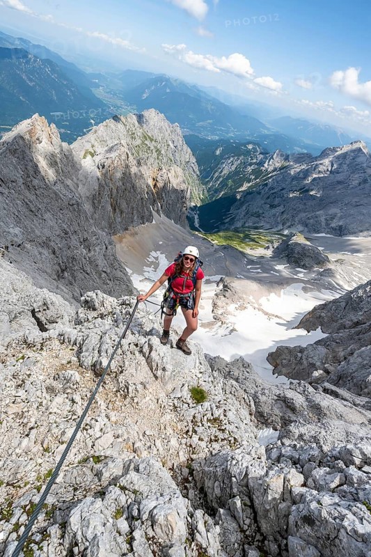 Mountaineer with helmet in a secured via ferrata, Zugspitze via ferrata, ascent to the Zugspitze, view of mountain basin with snow field of the Höllentalferner and Höllental, Wetterstein range, Wetterstein range, Bavaria, Germany