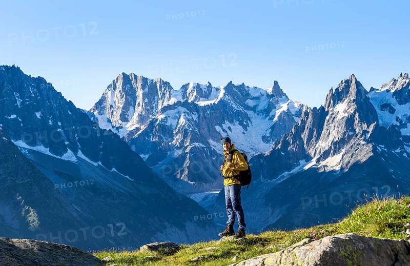Young man in front of impressive mountain landscape in morning light, picturesque mountain landscape with imposing mountain peaks and glaciers, Mer de Glace glacier, Grandes Jorasses in the background, Mont Blanc Massif, Chamonix-Mont-Blanc, Haute-Savoie, France