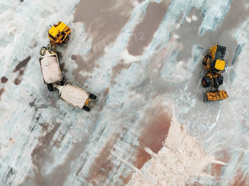 Excavator and lorry at a harvesting pan of the Walvis Bay Salt works. Aerial view. Drone shot. Walvis Bay, Namibia