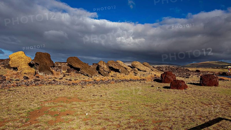 Fallen moai lie on a rocky area under a cloudy sky, the moai statues on Easter Island in the Pacific Ocean