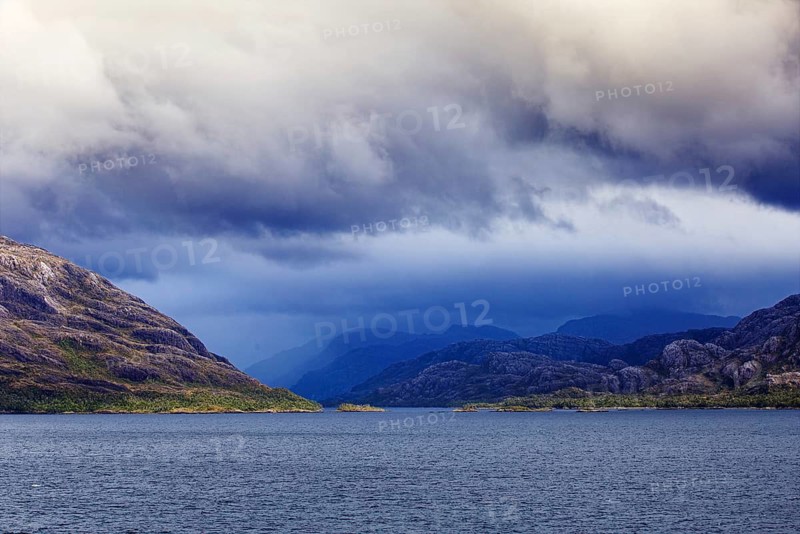 Dramatic scene with mountains and sea under a stormy cloudy sky, coordinates: 51°49'58.83 S, 73°41'30.04 W, Puerto Nateles, Chile, South America