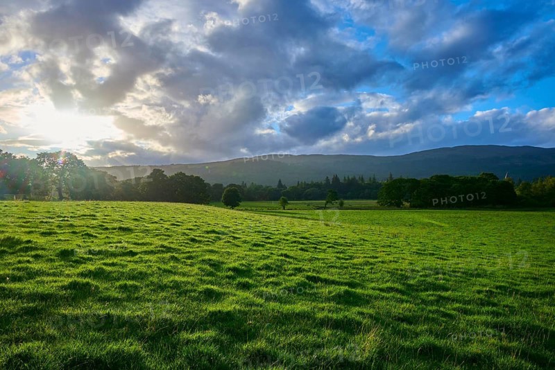 Green field under dramatic sky with sunset and mountains in the background, Fort Augustus, Loch Ness, Scotland, United Kingdom, United Kingdom
