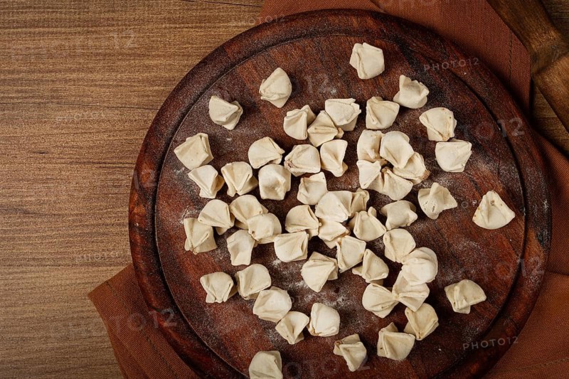 Traditional Turkish dumplings, raw, on a cutting board, top view, no people
