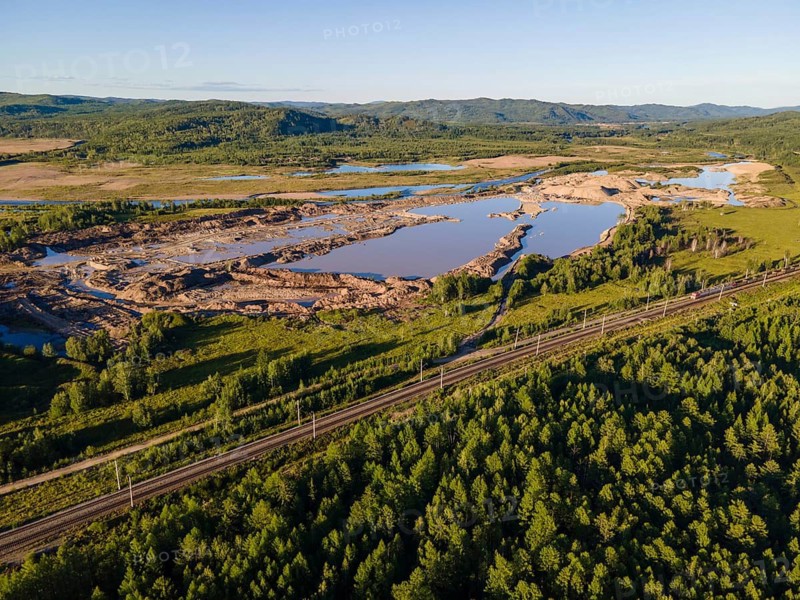 This scene showcases the breathtaking nature of Vladivostok, Russia. Lush greenery surrounds a river, reflecting the clear sky. The land formation indicates a serene environment, making it ideal for outdoor activities and nature lovers
