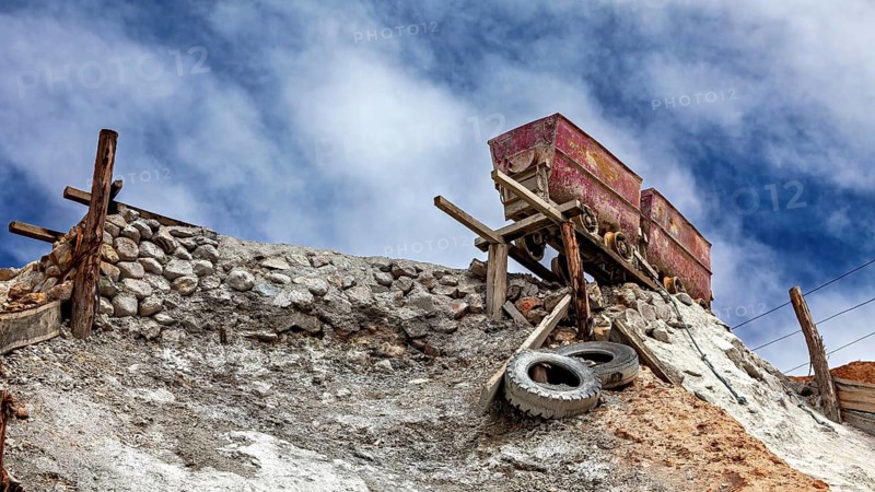 Two abandoned wagons stand on a hill under a blue sky, The Potosi Silver Mines on Cerro Rico in Bolivia