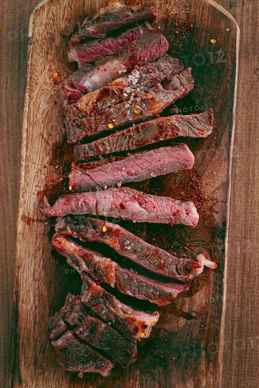 Medium rare, sliced rib eye steak, grilled cowboy steak, on a chopping board, close-up, homemade, top view, no people