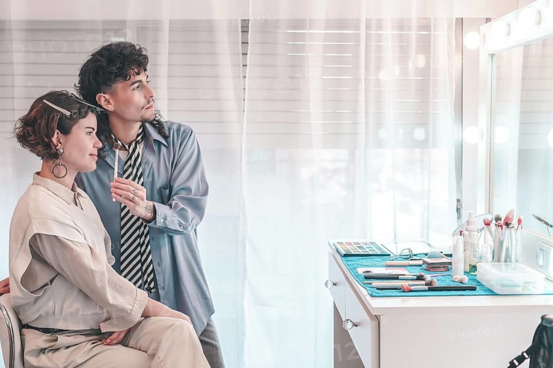 Professional makeup artist applying cosmetics on a model in a bright, modern beauty salon, highlighting diversity and inclusion in the beauty industry