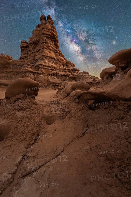Majestic sandstone structures stand under the glittering Milky Way in Goblin Valley State Park, Utah, USA. A serene blend of earthly textures and celestial beauty