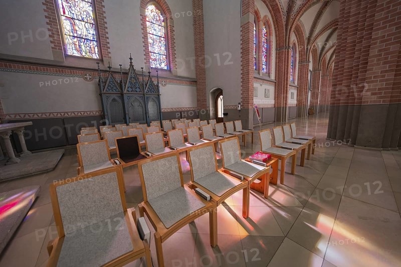 Church seating area with modern chairs, light shining through stained-glass windows, Sacred Heart, Bregenz, Austria