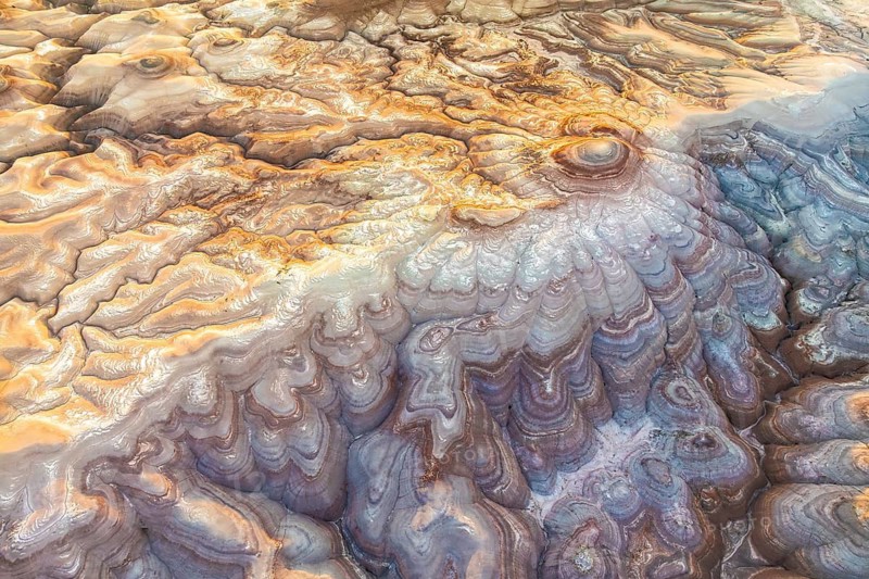 Captivating aerial view of golden bentonite formations in Utah, USA. The flowing patterns and earthy hues create an otherworldly landscape, showcasing natural beauty
