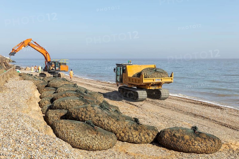 Emergency coastal defences work placing rock bags on beach to protect property, North Sea coast, Thorpeness, Suffolk, England, UK