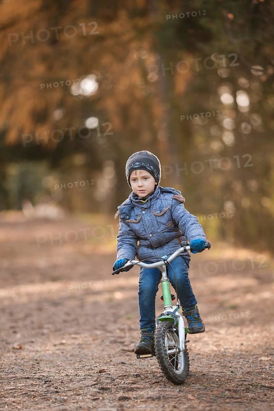 Six years old boy rides bicycle from the hill in the park