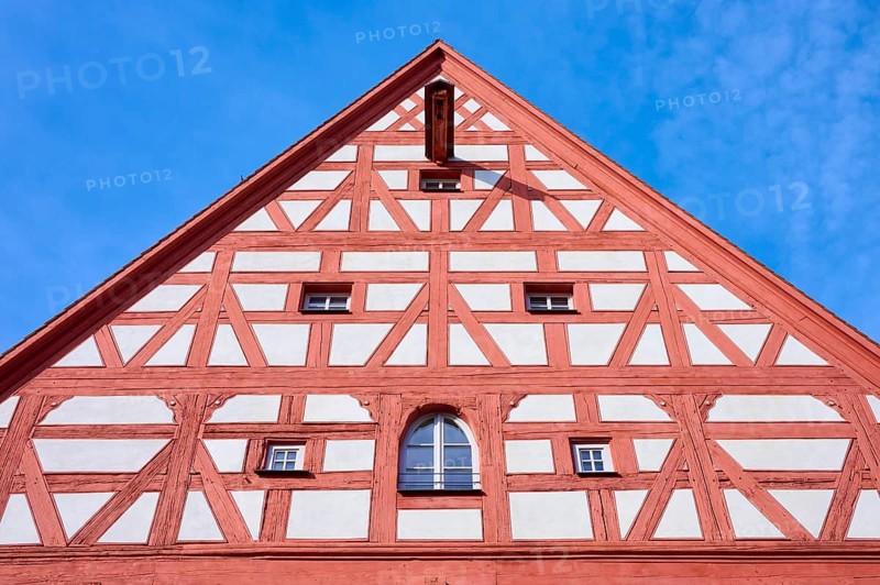 Detailed view of a timber-framed gable with symmetrical structures and windows against a blue sky, Wolframs-Eschenbach, Ansbach district, Middle Franconia, Bavaria, Germany