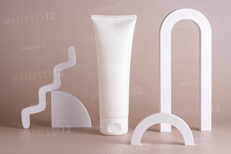 A minimalist skincare concept featuring a white tube surrounded by sleek geometric shapes on a beige background, embodying simplicity and elegance in beauty product design