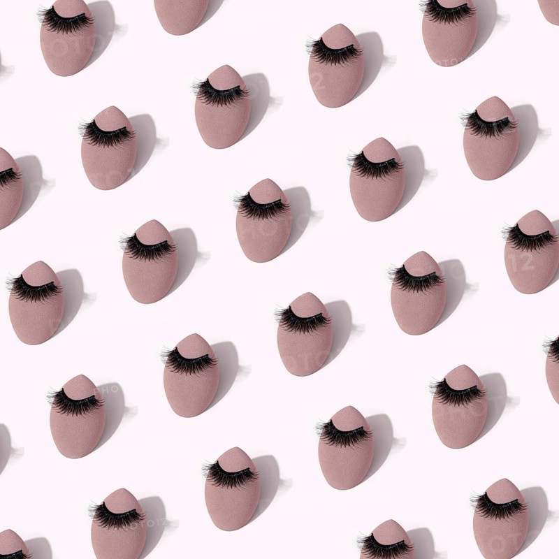 A seamless pattern featuring makeup sponges adorned with false eyelashes set against a soft background, emphasizing beauty and cosmetic tools in a stylish design