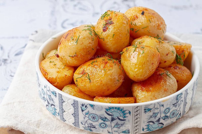 Baked new potatoes, with butter and dill, on a white plate, at home, no people