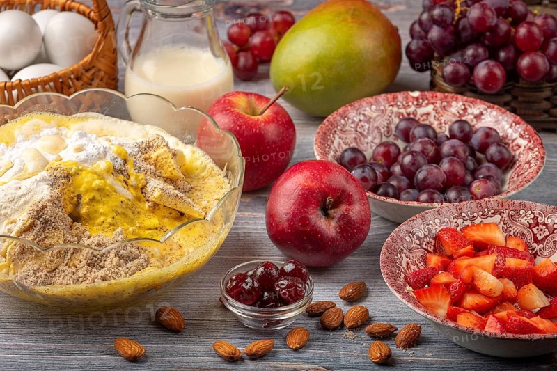 Apple, grapes, mango and strawberries next to a bowl of baking ingredients