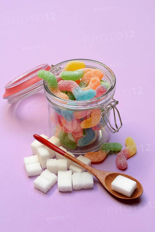Lots of colorful jelly sweets in glass containers and sugar cubes, sugar consumption