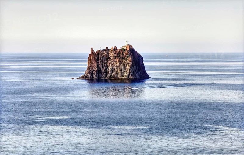 Fantastic view of Strombolicchio rock in the sea with a lighthouse surrounded by calm water, Stromboli Lipari Islands Sicily Italy