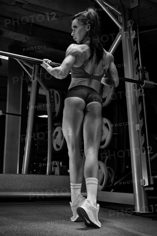Fitness woman posing in the gym. Bodybuilding concept. View from the back.