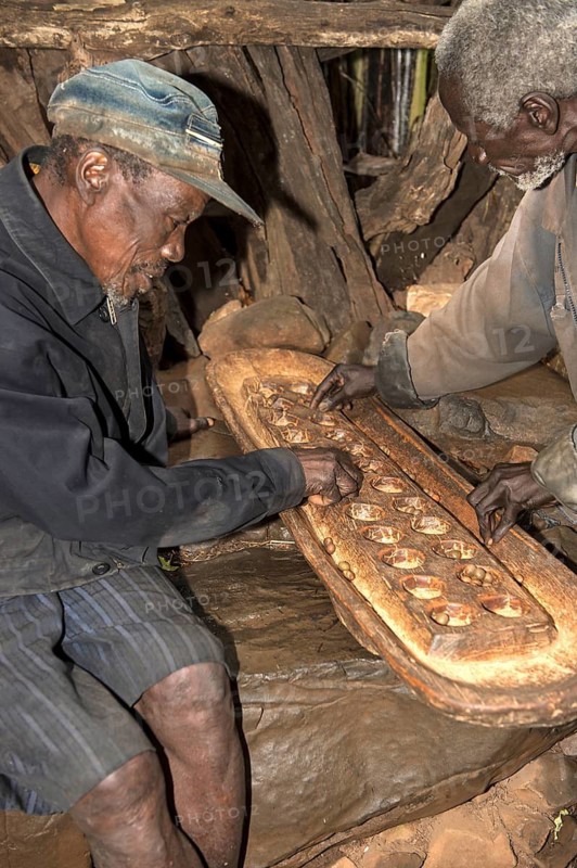 Two men from the Konso ethnic group play the board game Gebeta, a variant of the Mancala board game, Omo Valley, Ethiopia