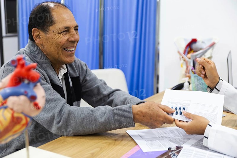 An elderly male patient receives attentive care from a young female doctor in a Latin American hospital, highlighting professional medical service and patient trust