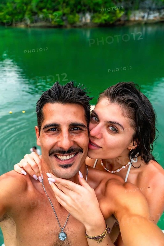 Tourists taking a selfie in the beautiful sugba lagoon in siargao island, philippines, enjoying their summer vacation