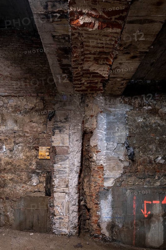 Exposed brick and concrete wall featuring signs of ongoing construction. Visible repairs highlight the texture and aged look, symbolizing a work in progress