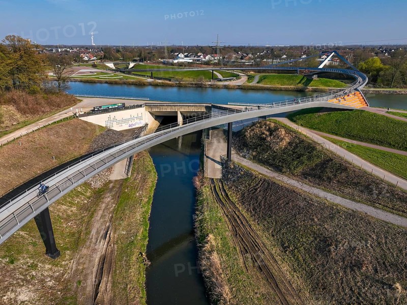 Castrop-Rauxel, North Rhine-Westphalia, Ruhr region, Germany - Sprung bridge over the Emscher, a footbridge and cycle path across the Emscher and the Rhine-Herne Canal. EMSCHERLAND adventure park, new nature and water adventure park on the restored Emscher, at the Emscher water cross with the Rhine-Herne Canal on the city limits of Recklinghausen and Castrop-Rauxel. Flood protection through area expansion. The ecological focus at the confluence of the Suderwicher Bach and Emscher rivers will also be a future garden of the IGA 2027 International Garden Exhibition. Before the restoration, the river system of the Emscher was an open, aboveground waste water channel, mixed water channel with surface water and waste water