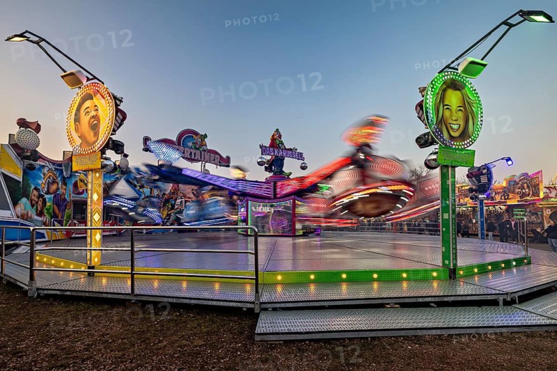 A spinning ride with colorful lights and blurred movements at dusk, carousel and the hustle and bustle of summer profit in Eisenach