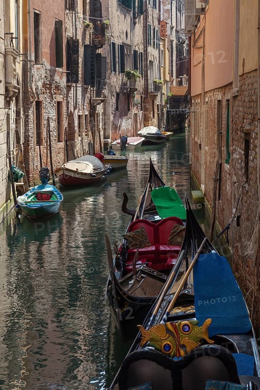 Gondolas on a narrow waterway surrounded by historic buildings and a peaceful atmosphere, Venice, Italy
