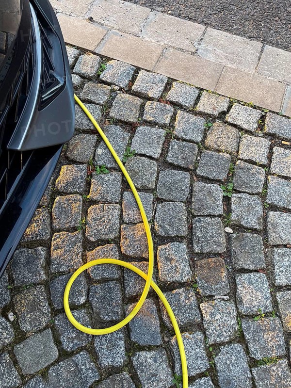 A yellow charging cable of an electric car lies on paving stones, Düsseldorf, Germany