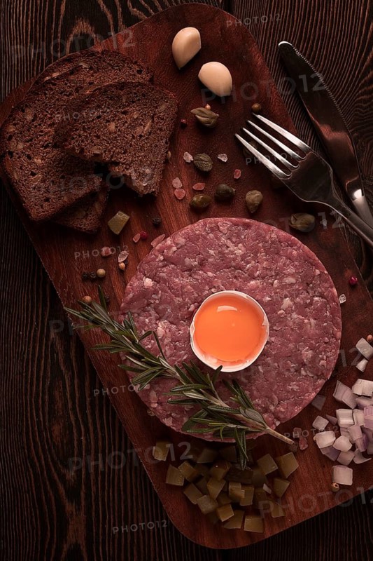 Beef tartare, with egg, capers, gherkins and bread, toned, top view, close up, horizontal, no people