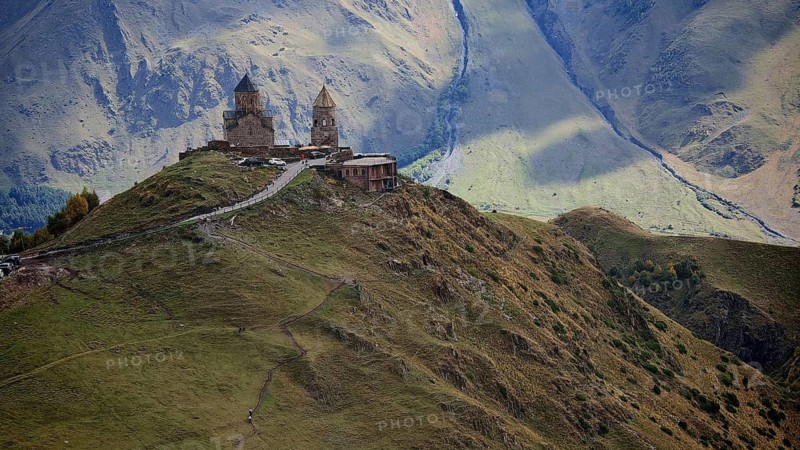 Historic Gergeti church on a hill surrounded by majestic mountains, Stepantsminda, Caucasus, Georgia