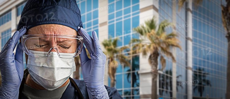 Grimacing Female Doctor or Nurse Wearing Scrubs, Protective Face Mask and Goggles