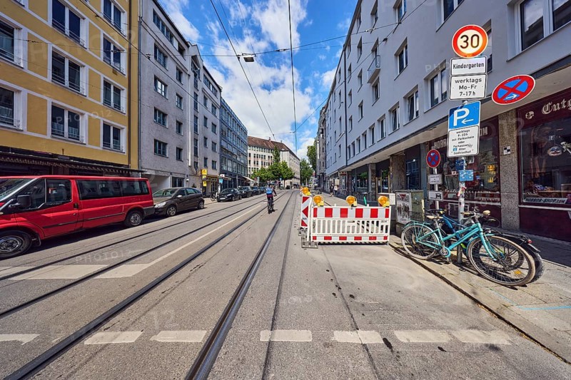 Residential and commercial buildings, general architecture, roadway, sidewalk, parking strips with cars, fenced construction site, tram tracks, overhead lines, traffic signs, absolute stopping ban, parking, Tempo 30 sign with additional signs kindergarten and weekdays Mon-Fr 7-17 h, bicycles, blue sky, cumulus clouds, Müllerstraße, Munich, state capital, district-free city, Bavaria, Germany