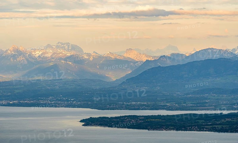 A breathtaking aerial photograph captures the serene beauty of Lake Leman with the majestic Alps in the background during a peaceful dusk