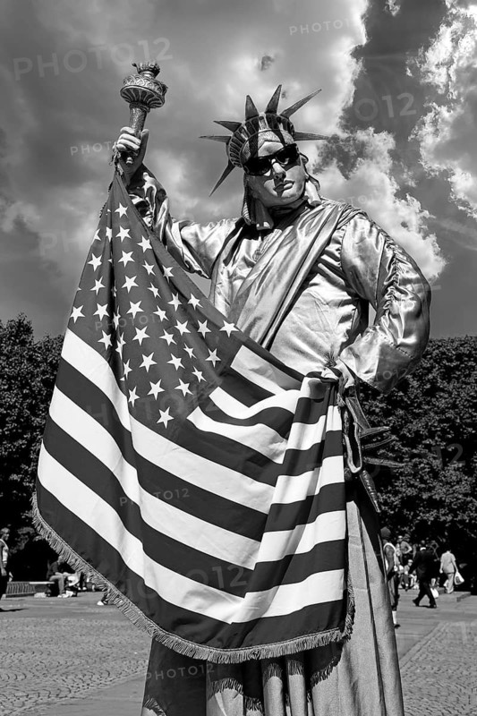 Man with US flag disguised as a statue of Liberty in Central Park, New York City, USA