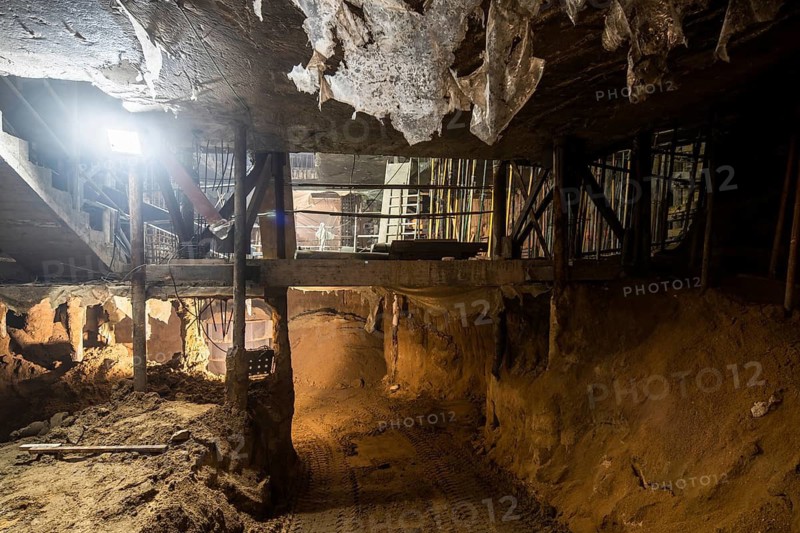 A captivating view of an underground tunnel under construction, showcasing raw earth, metal supports, and scattered debris, highlighting the work in progress