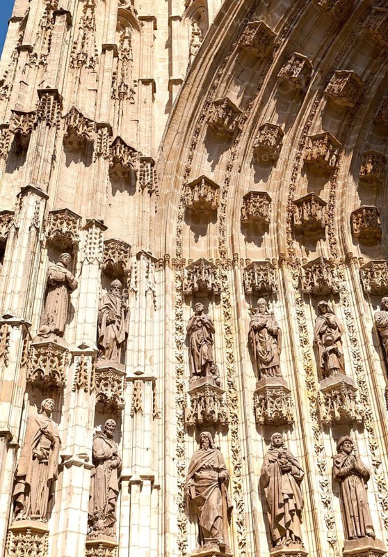 Detail of carved stonework of cathedral frontage showing statues of saints, Seville, Spain