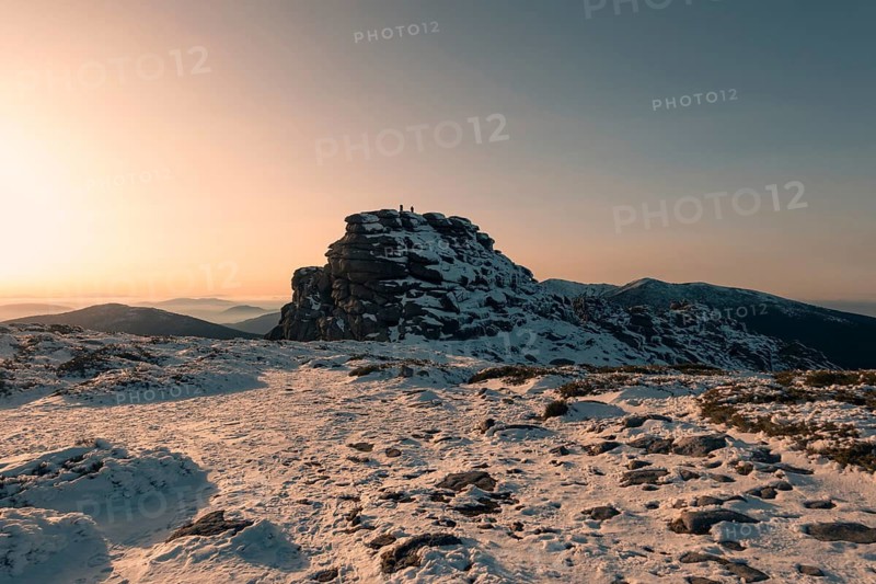 Captivating winter scene of Siete Picos in Madrid's Guadarrama Mountains. The snow-covered landscape glows under a serene, golden sunset, offering a tranquil view