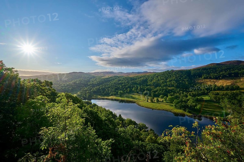 Brilliant sun over a green landscape with clouds and a lake, Queens View, Fincastle, Pitlochry, Scotland, United Kingdom, Great Britain